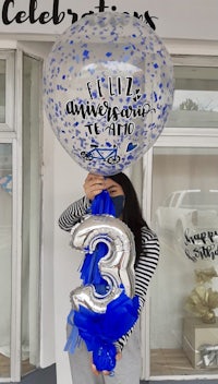 a woman holding a blue and silver balloon in front of a store