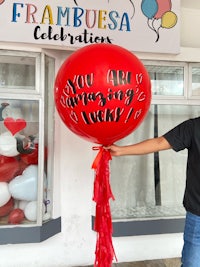 a man holding a red balloon in front of a store