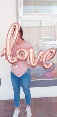 a woman holding up a balloon that says love