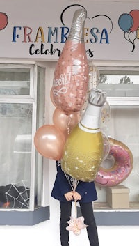 a woman holding balloons in front of a store