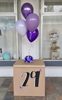 a box with purple balloons and a number on it