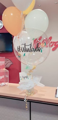 a counter with balloons and a sign