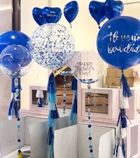 a display of blue and white balloons with tassels