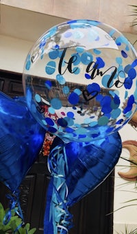 a blue and white balloon with confetti on it