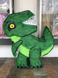 a green t - rex pinata in front of a store