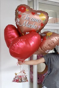 a woman holding balloons with the words te amo mucho