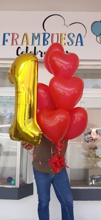 a man holding a red and gold balloon with the number 1 on it