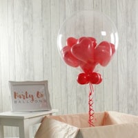 a balloon filled with red heart balloons on a table