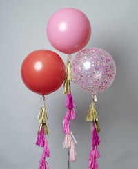 three pink and gold balloons with tassels