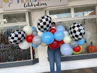 a woman holding a balloon garland in front of a store