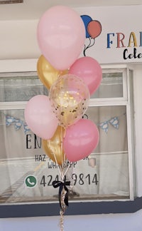 a bouquet of pink and gold balloons in front of a store