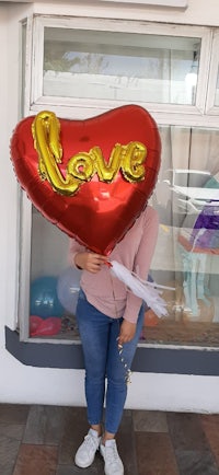 a woman holding a heart shaped balloon with the word love