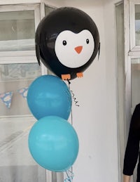 a woman holds a balloon with a penguin on it