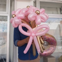 a man holding a bouquet of pink balloons